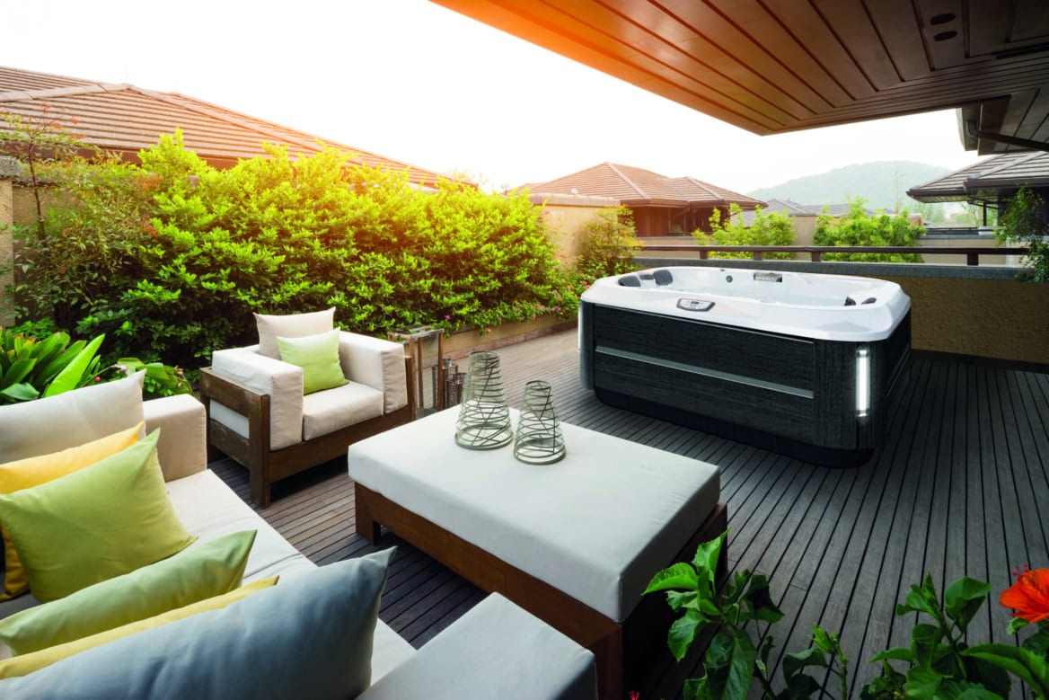 Terras met jacuzzi en moderne meubels bij zonsondergang.