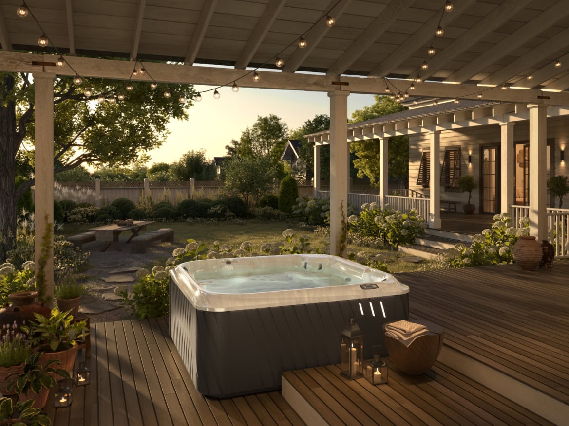 Tuin met jacuzzi en terrasverlichting bij zonsondergang.